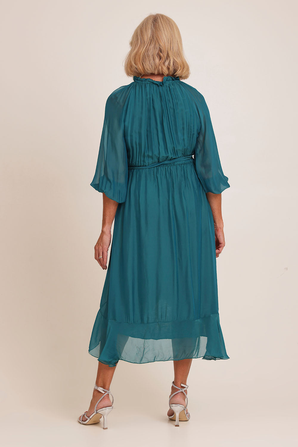Model Sandy wearing the Long Sleeve Silk Frill Tied Neck Knee Length Dress in colour Teal (Green), from the back