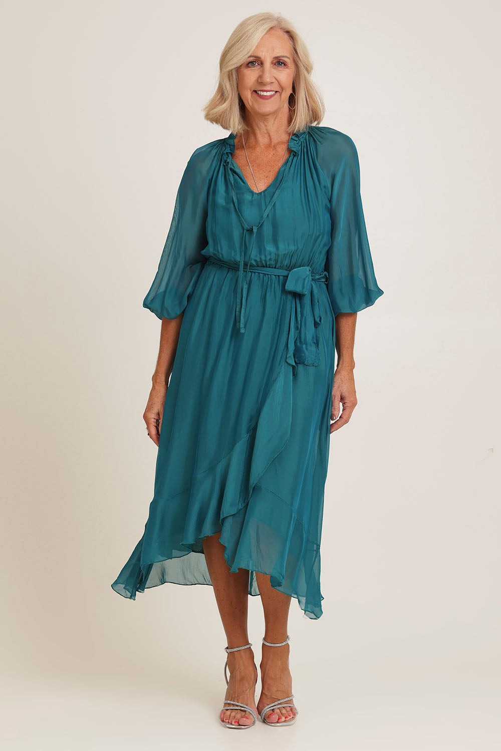 Model Sandy wearing the Long Sleeve Silk Frill Tied Neck Knee Length Dress in colour Teal (Green), from the front, showing the whole outfit