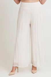 Model Chanel wearing the Silk Pant in colour Ivory, from the front, cropped image