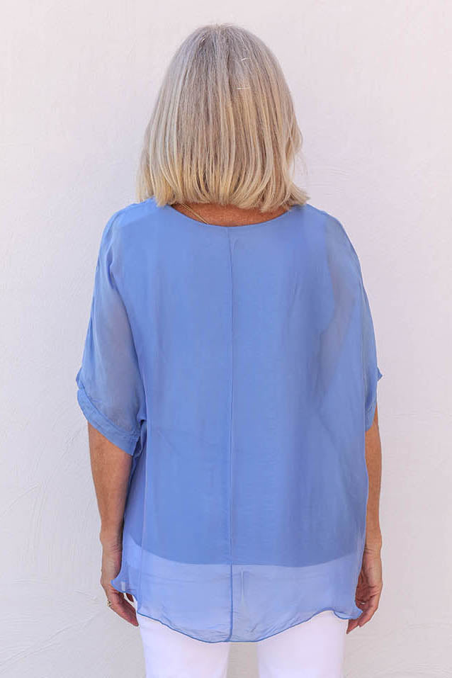 Model Sandy wearing the Silk Blend Three Layer Raw Edge Top in colour Blueturco (Blue), from the back