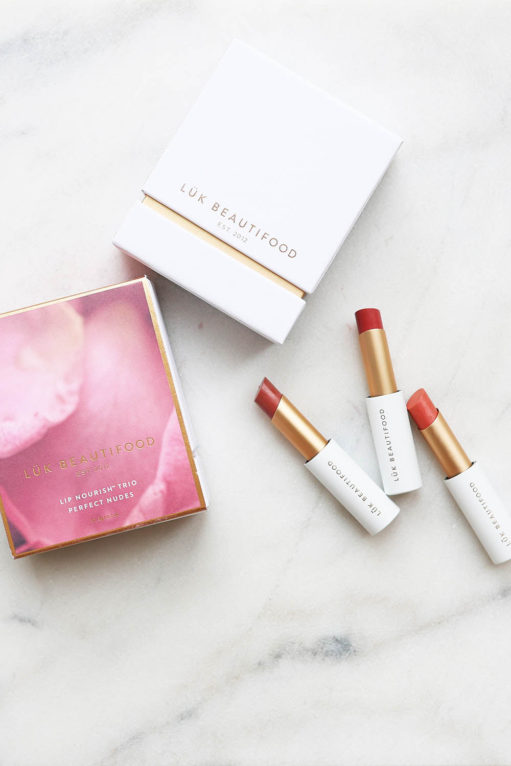A model wearing the Lip Nourish Trio in colour Nudes, from the front, showing the whole outfit