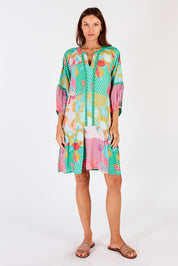 A model wearing the Camargue Dress in colour Lagoon (Green), from the front, showing the whole outfit
