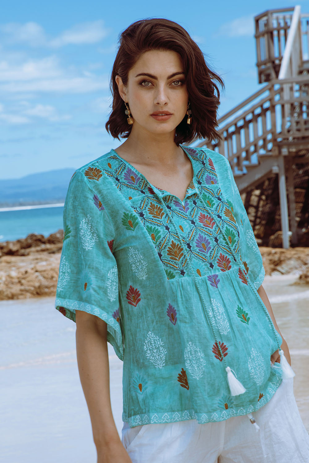 A model wearing the Dixie Top in colour Sea (Green), from the front, showing the whole outfit