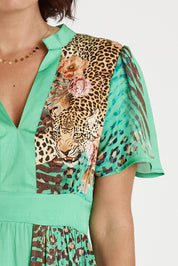 A model wearing the Maasai Midi Dress in colour Emerald (Green), from the front, cropped image