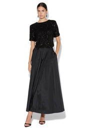 A model wearing the Lux Maxi Skirt in colour Black (Black), from the front, showing the whole outfit