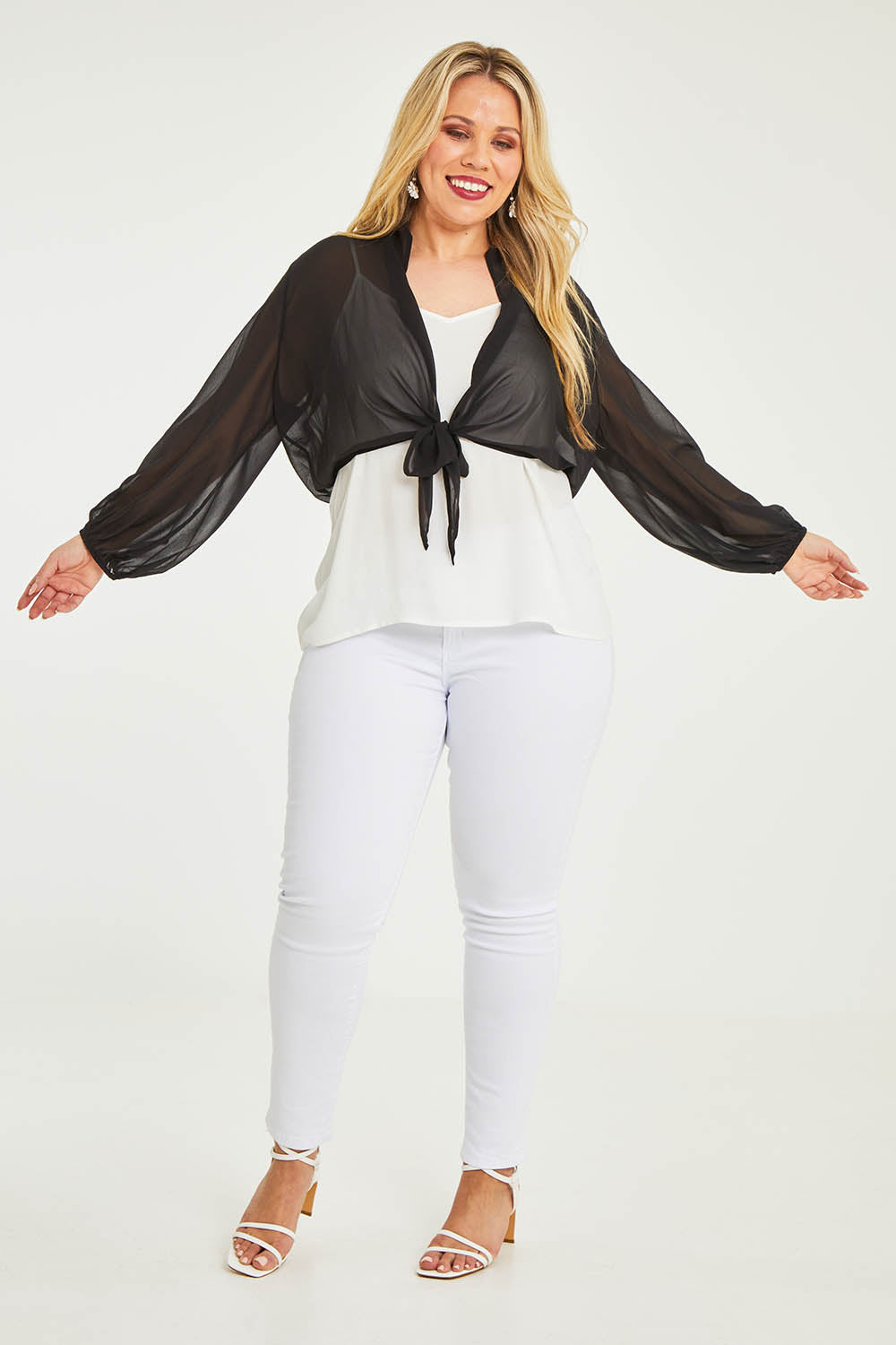 Model Katie wearing size 16 of the Penelope Shrug in colour Black (Black), from the front, showing the whole outfit