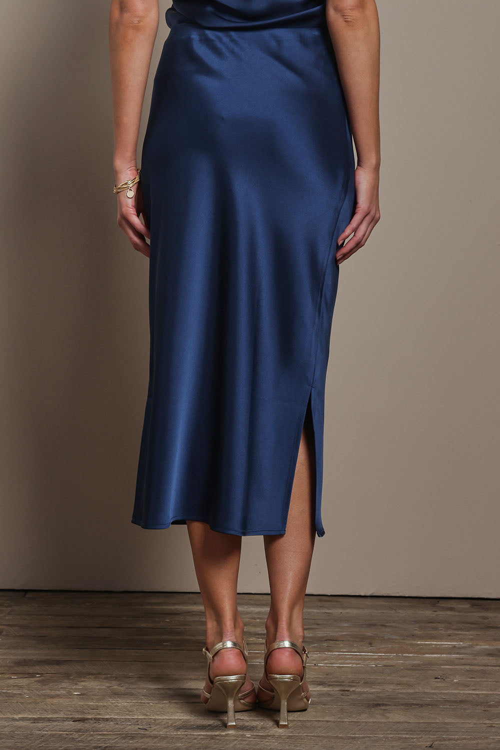 Model Madeline wearing size 10 of the Loulou Satin Skirt in colour Steelblue (Blue), from the back