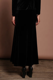 Model Madeline wearing size 10 of the Marlene Velvet Skirt in colour Black (Black), from the back