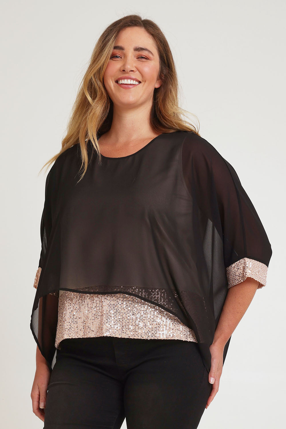 Model Chanel wearing size 16 of the Ria Top in colour Blackgold (Black), from the front, cropped image