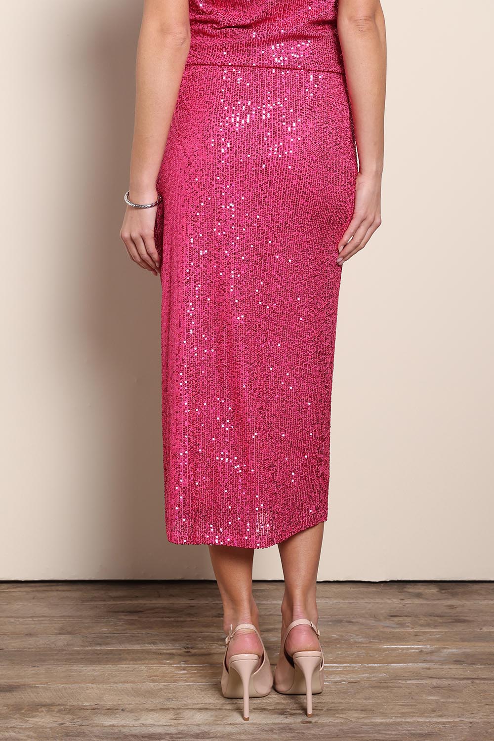 Model Maddiec wearing size 10 of the Reegan Sequin Skirt – Cerise in colour Cerise, from the back