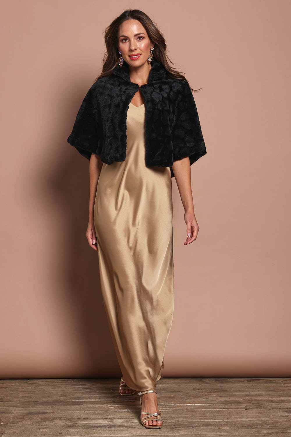 Model Madeline wearing size 10 of the Daphne Faux Fur Cape in colour Black (Black), from the front, showing the whole outfit