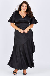 Model Mae wearing size 18 of the Fleur Dress in colour Black (Black), from the front, showing the whole outfit