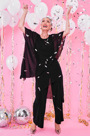 Model Luisa wearing size 10 of the Sandra Jumpsuit in colour Black (Black), from the front, showing the whole outfit
