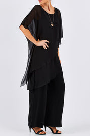 Model Monique wearing size 8 of the Sandra Jumpsuit in colour Black (Black), from the front, cropped image