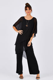 Model Monique wearing size 8 of the Sandra Jumpsuit in colour Black (Black), from the front, showing the whole outfit