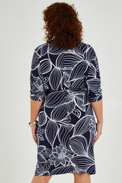 Model Maddy wearing size 16 of The Printed Nancy Dress in colour Navyleaves (Blue), from the back