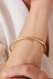 A model wearing the Simplicity Gold Bangle in colour Gold (Metallics), from the front, showing the whole outfit