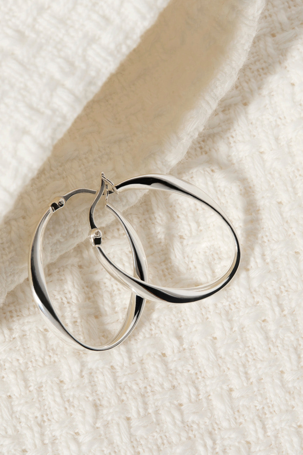 A model wearing the Cinta Hoop Earrings in colour Silver (Metallics), from the front, showing the whole outfit