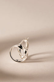 A model wearing the Eddy Hoop Earrings in colour Silver (Metallics), from the front, showing the whole outfit