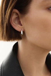 A model wearing the La Muse Silver Stud Hoop Earring in colour Silver (Metallics), from the front, cropped image