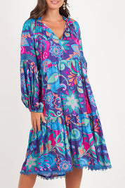 A model wearing the Molly Dress in colour Enigma (Blue), from the front, cropped image
