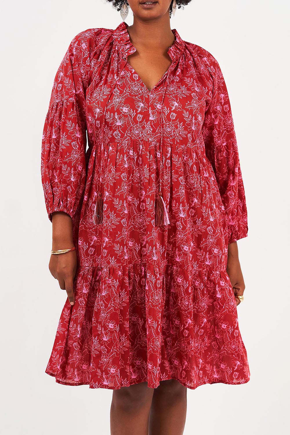A model wearing the Molly Cotton Dress in colour Serenityma (Red), from the front, cropped image