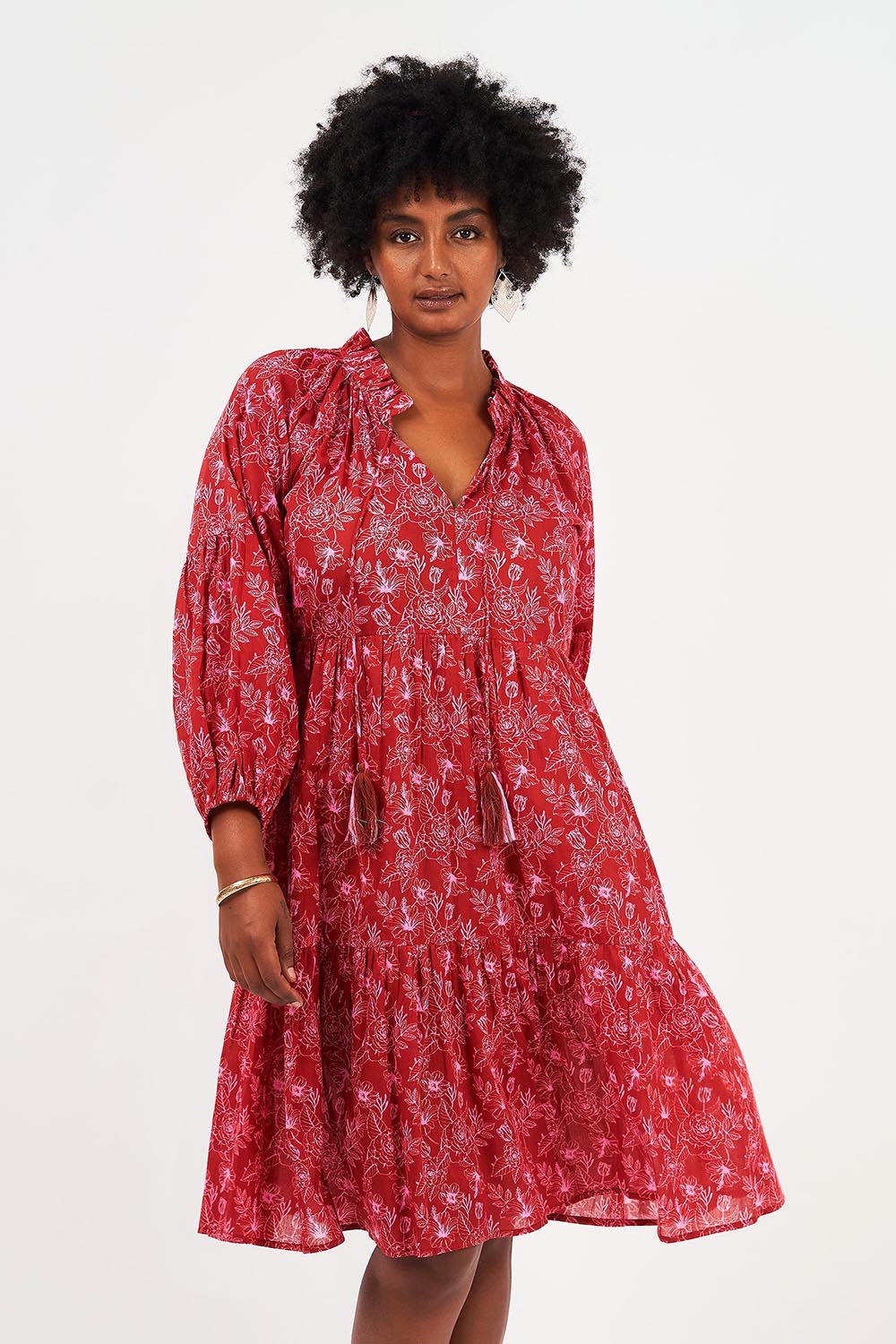 A model wearing the Molly Cotton Dress in colour Serenityma (Red), from the front, cropped image