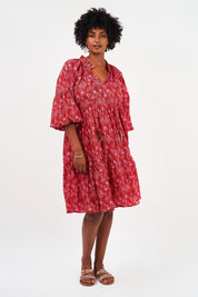 A model wearing the Molly Cotton Dress in colour Serenityma (Red), from the front, showing the whole outfit