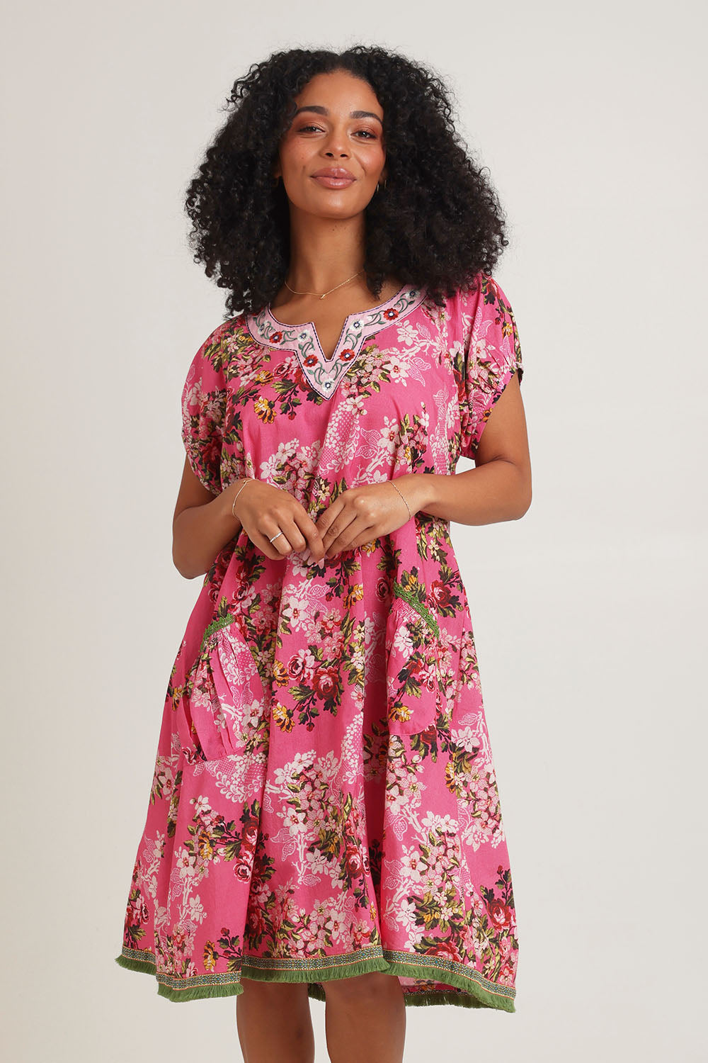 Model Ziara wearing size S of the Sao Paulo Cotton Dress in colour Folly (Pink), from the front, cropped image