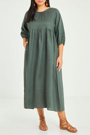 Model Terri-Leigh wearing size 14 of the Linen Gathered Waist Dress in colour Green (Green), from the front, cropped image