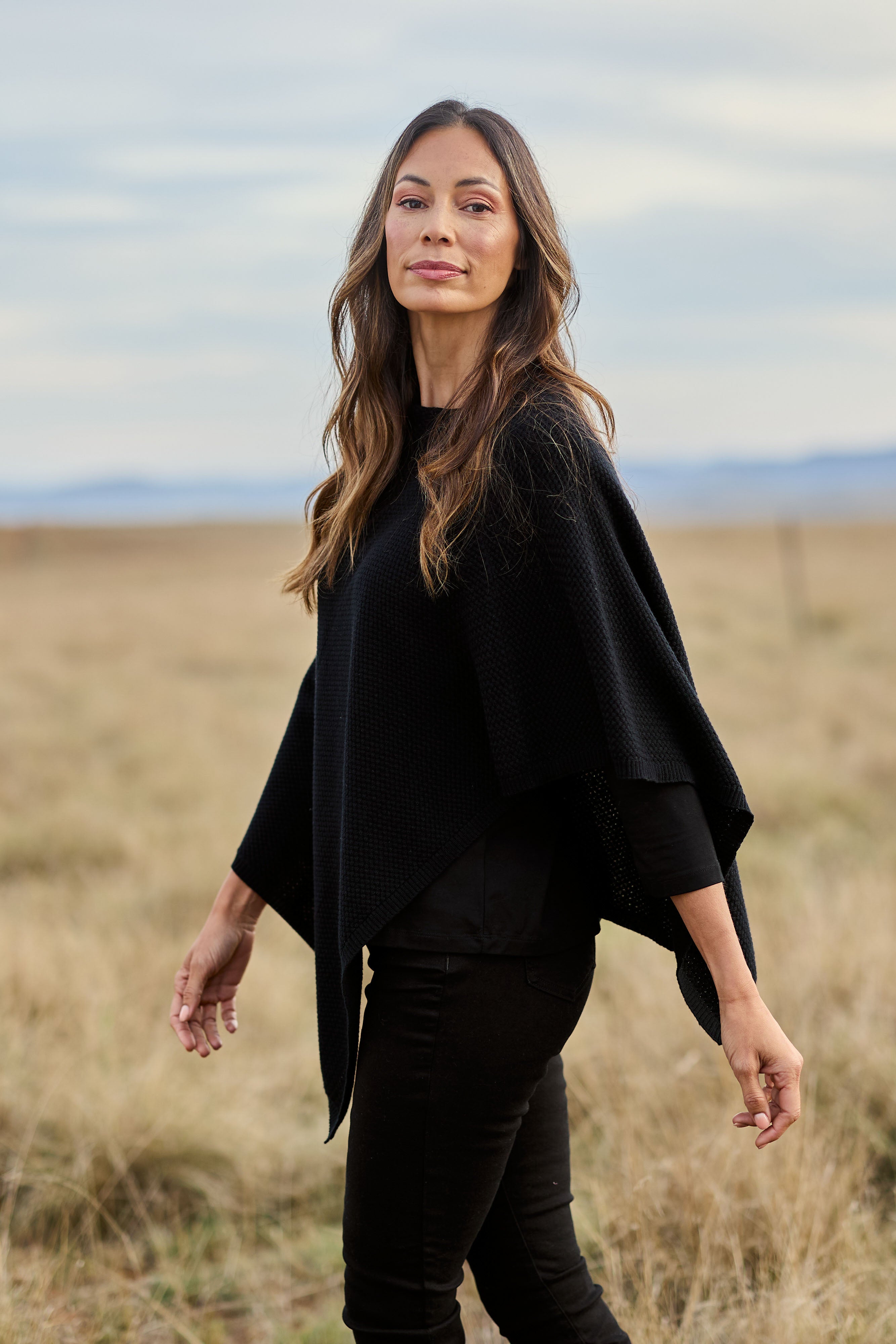 Model Amanda wearing size S of the Cotton Cashmere Wool Poncho in colour Black (Black), from the front, showing the whole outfit