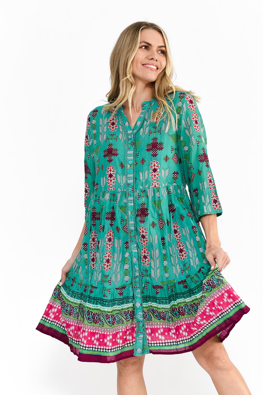 A model wearing the Border Cotton Dress in colour Aztec1 (Green), from the front, cropped image