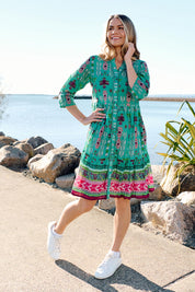 A model wearing the Border Cotton Dress in colour Aztec1 (Green), from the front, showing the whole outfit