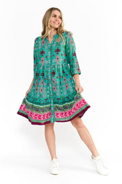 A model wearing the Border Cotton Dress in colour Aztec1 (Green), from the front, showing the whole outfit