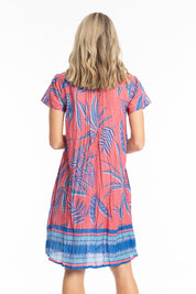 Model Genericm wearing size sample of the Nicola Cotton Dress - Coral in colour Coral, from the back