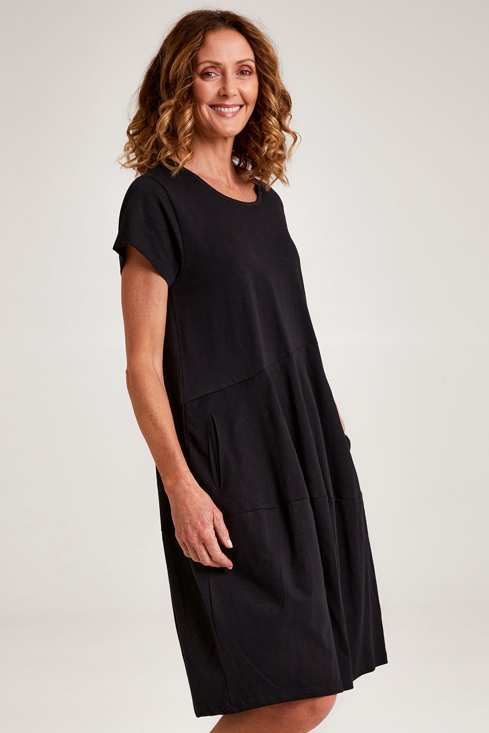 Model Emma wearing size 10 of the Essentials Organic Cotton Bubble Dress in colour Black (Black), from the front, cropped image