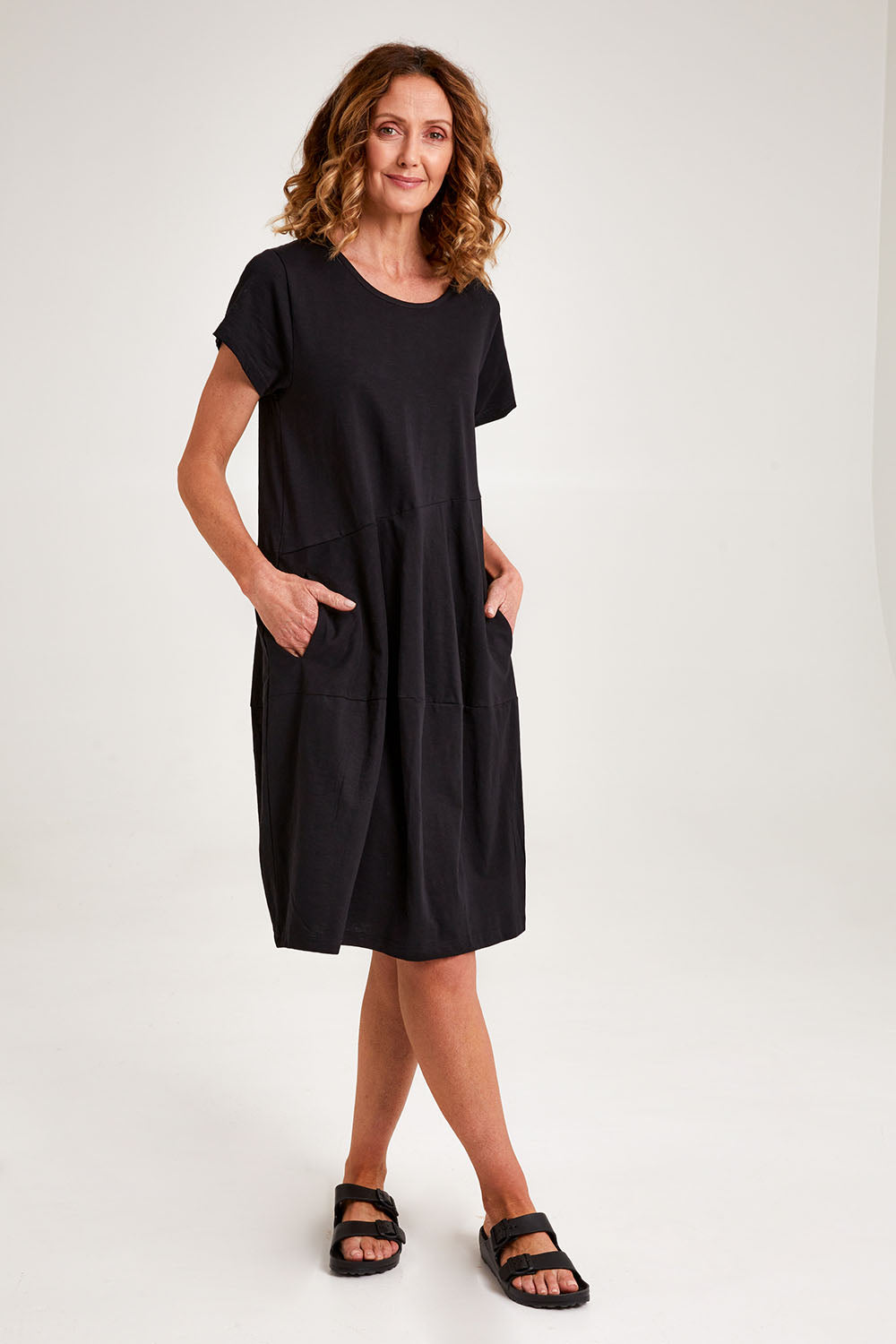 Model Emma wearing size 10 of the Essentials Organic Cotton Bubble Dress in colour Black (Black), from the front, showing the whole outfit