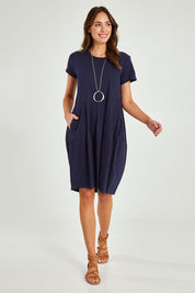 Model Madeline wearing size 10 of the Essentials Organic Cotton Bubble Dress in colour Navy (Blue), from the front, showing the whole outfit