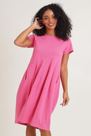 Model Ziara wearing size 10 of the Essentials Organic Cotton Bubble Dress in colour Pink (Pink), from the front, cropped image