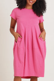 Model Ziara wearing size 10 of the Essentials Organic Cotton Bubble Dress in colour Pink (Pink), from the front, cropped image