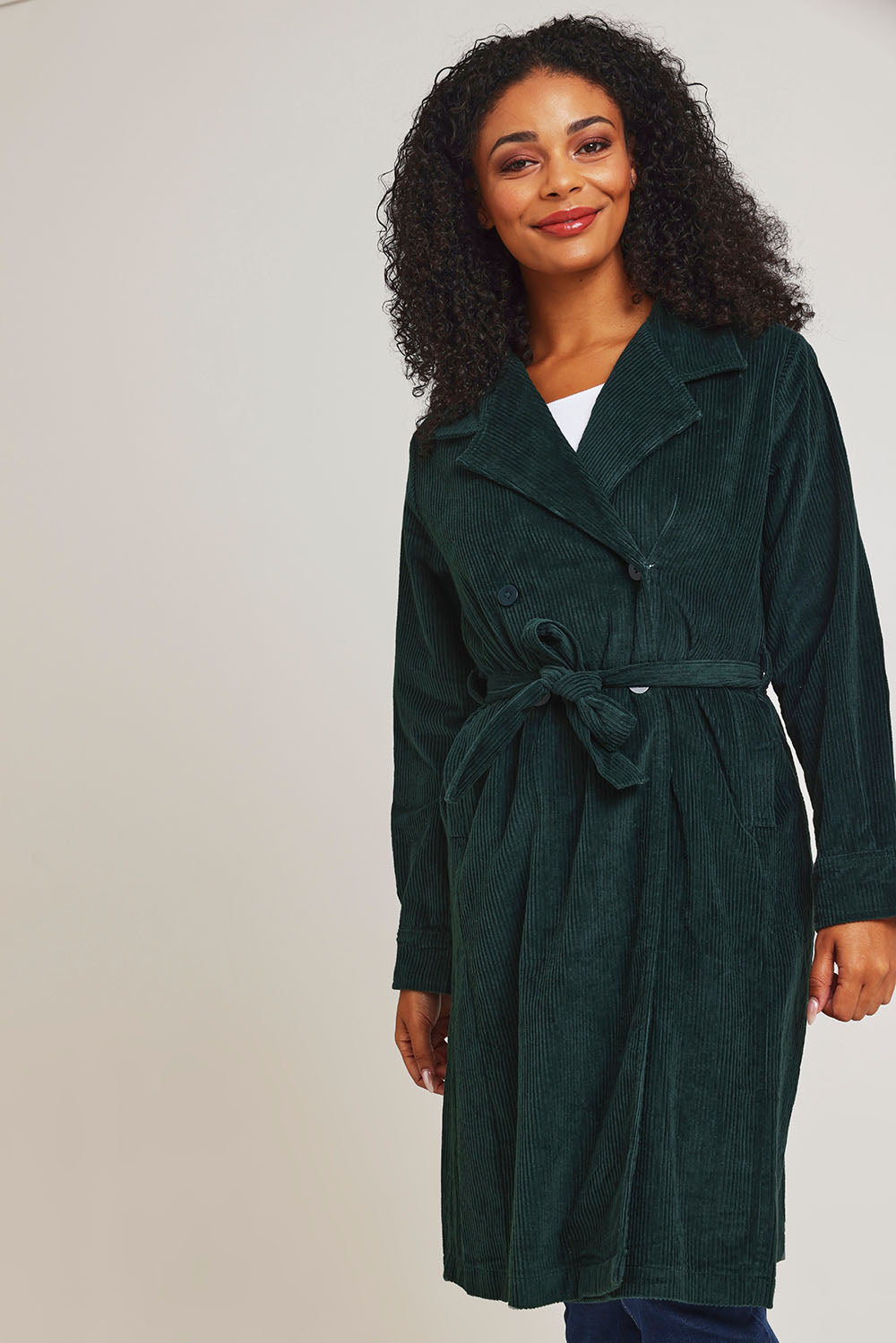 Model Ziara wearing size 10 of the Essentials Cotton Corduroy Trench Coat in colour Pine (Green), from the front, cropped image
