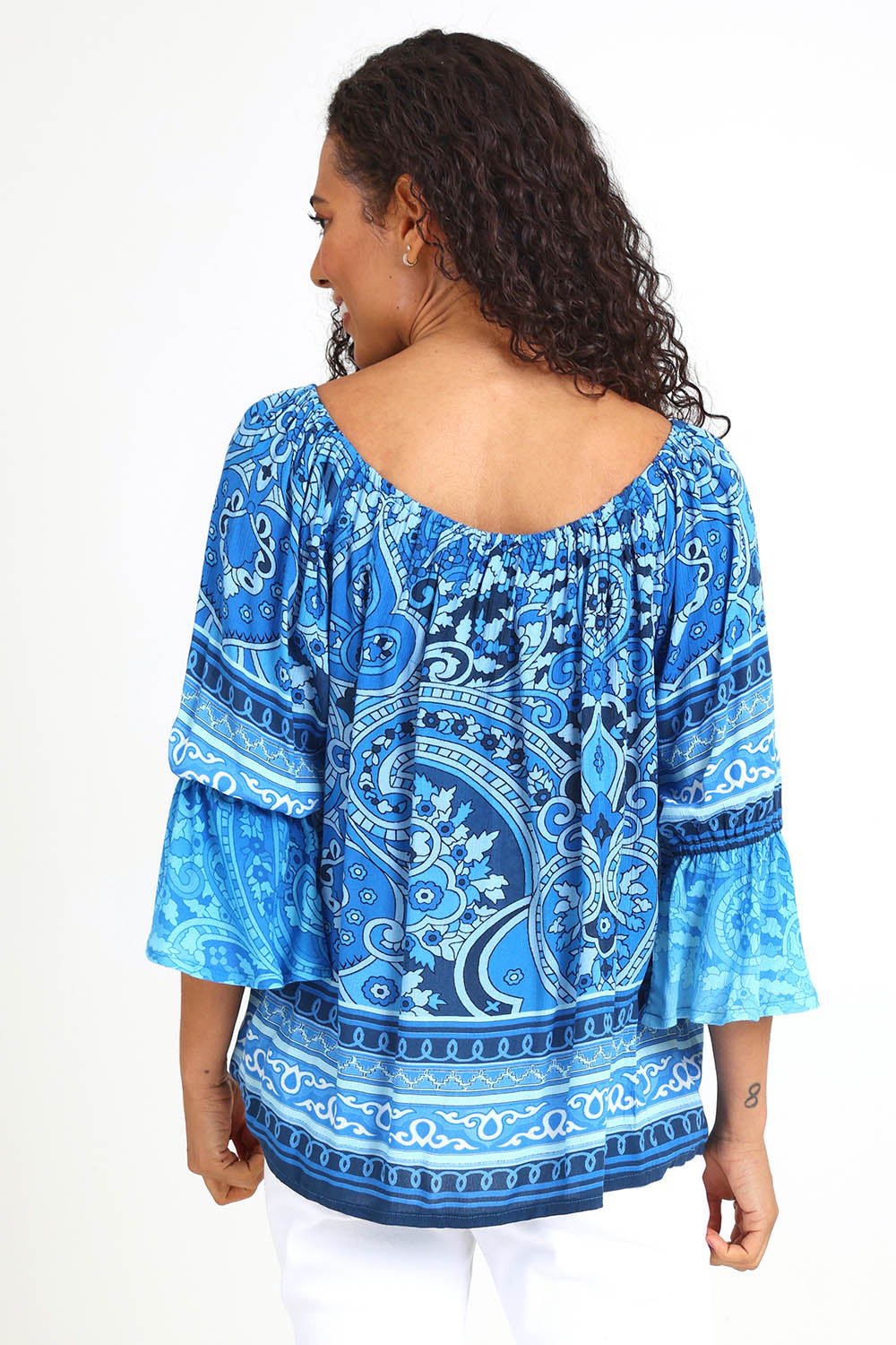 Model Pamelar wearing size 10 of the Boho Tassel Top – Blue in colour Blue, from an angle