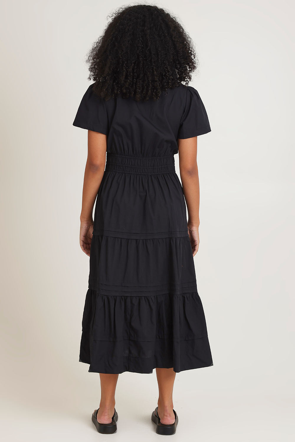 Model Ziara wearing size 10 of the Essentials Organic Cotton Poplin Maxi Ruched Waist Dress in colour Black (Black), from the back