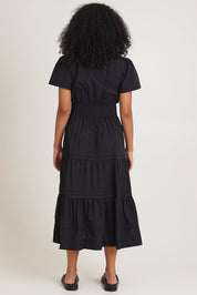 Model Ziara wearing size 10 of the Essentials Organic Cotton Poplin Maxi Ruched Waist Dress in colour Black (Black), from the back