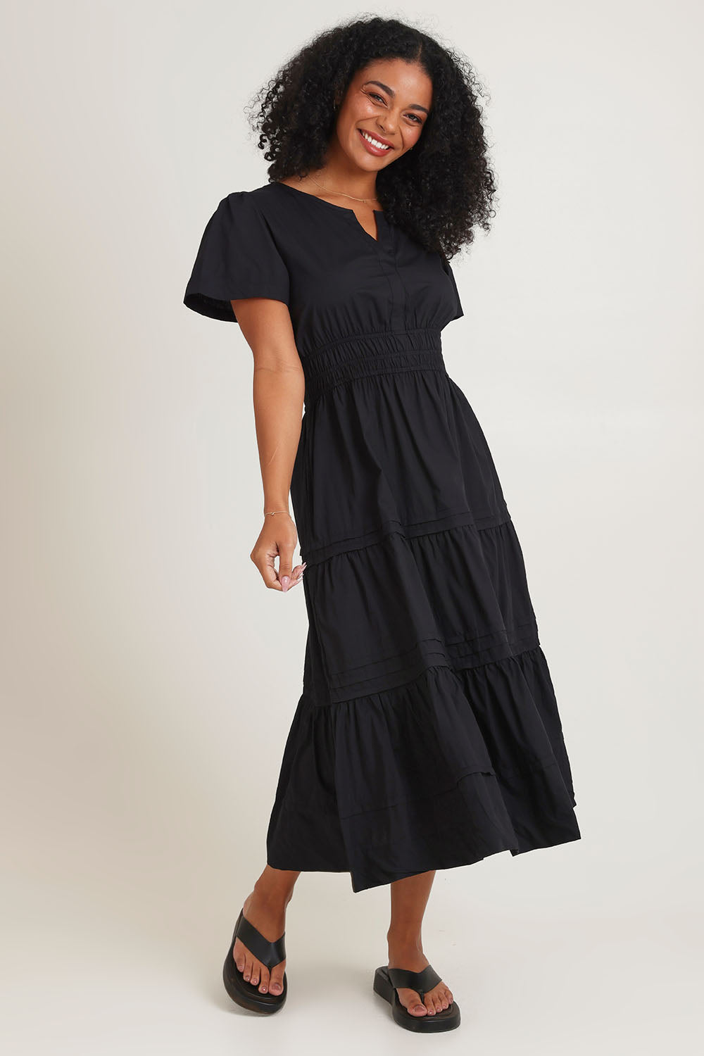 Model Ziara wearing size 10 of the Essentials Organic Cotton Poplin Maxi Ruched Waist Dress in colour Black (Black), from the front, showing the whole outfit