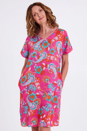 Model Emma wearing size 10 of the Symi Reversible Shift Organic Cotton Dress in colour Aquapink (Pink), from the front, cropped image
