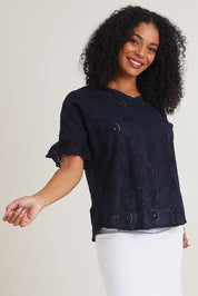 Model Ziara wearing size 10 of the Essentials Broderie Cotton Top in colour Navy (Blue), from the front, cropped image