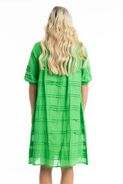 A model wearing the Essentials Organic Cotton Gauze Pleated  Dress in colour Parakeet (Green), from the back