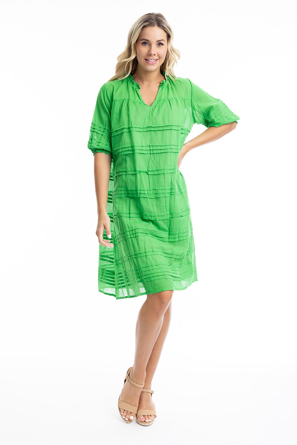 A model wearing the Essentials Organic Cotton Gauze Pleated  Dress in colour Parakeet (Green), from the front, showing the whole outfit