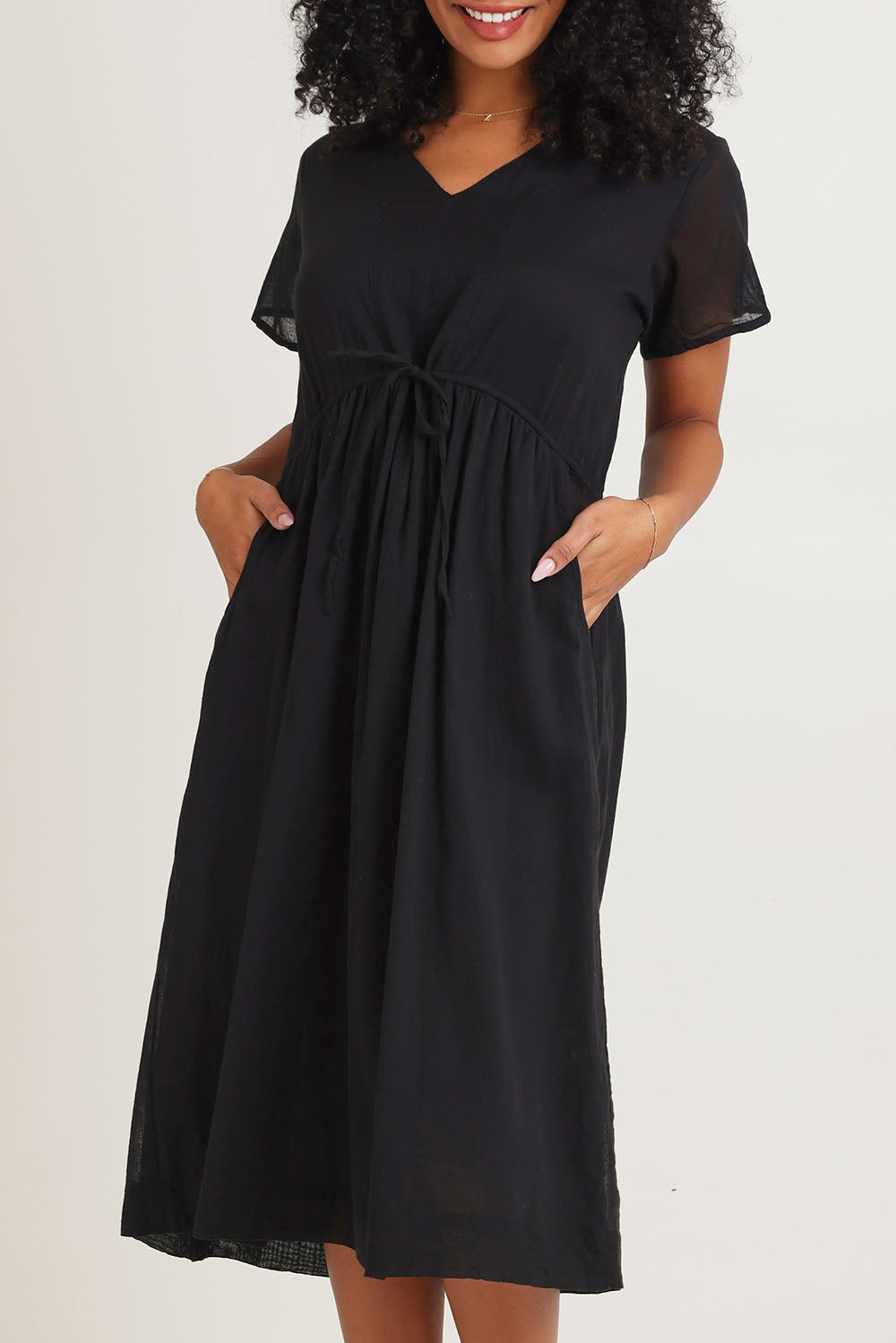 Model Ziara wearing size 10 of the Essentials Tie Waist Cotton Dress in colour Black (Black), from the front, cropped image